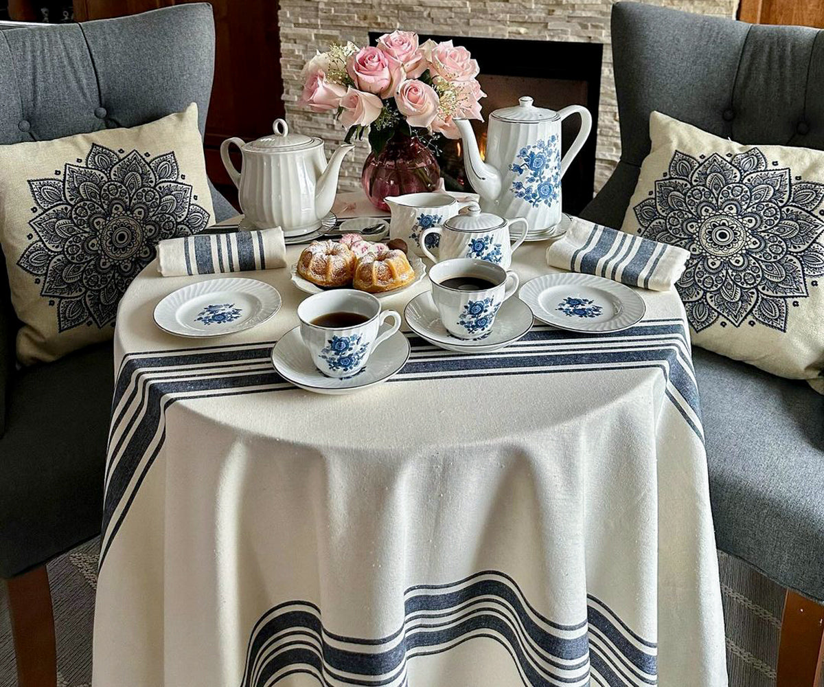 An elegantly set dining table with oval-shaped placemats made of woven natural fibers, light-colored tablecloth  and a centerpiece with fresh flowers in a cozy dining room ambiance.