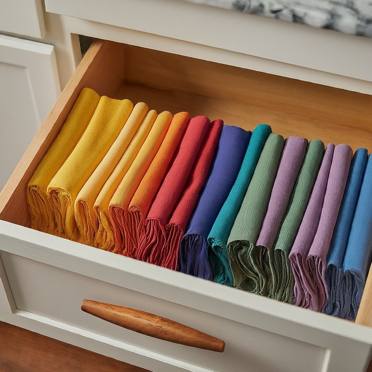 A stack of high-quality cloth napkins in various vibrant colors, neatly folded and arranged on a table.