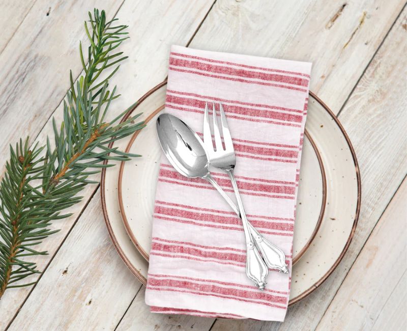 Beige linen napkins folded neatly on a wooden table, with elegant tableware and a cozy country-style dining ambiance