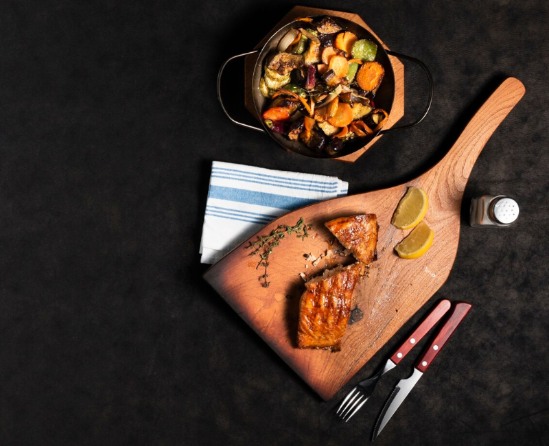 A variety of grilled dishes on a cotton tablecloth, including salmon, ribs, and hamburgers