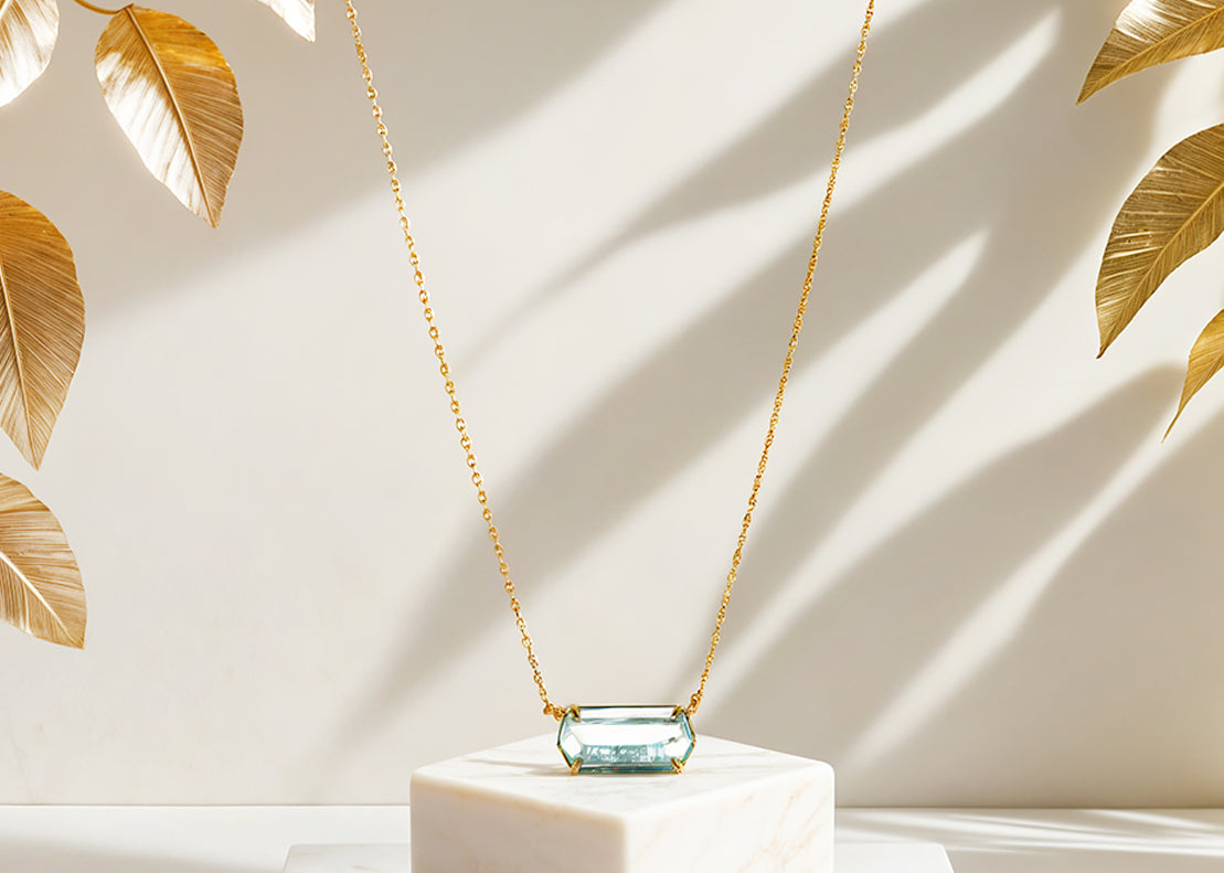 Gold plated chain necklace with a blue pendant.