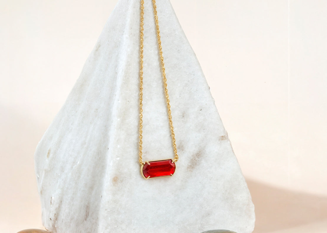 Stylish gold necklace with red pendant.