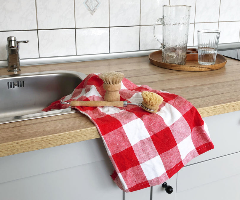 Plaid kitchen towels with a colorful checkered pattern hanging in a kitchen or draped over a counter.