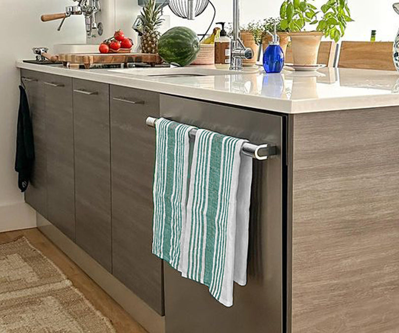 Set of linen kitchen towels hanging on a rack or draped over a kitchen counter.