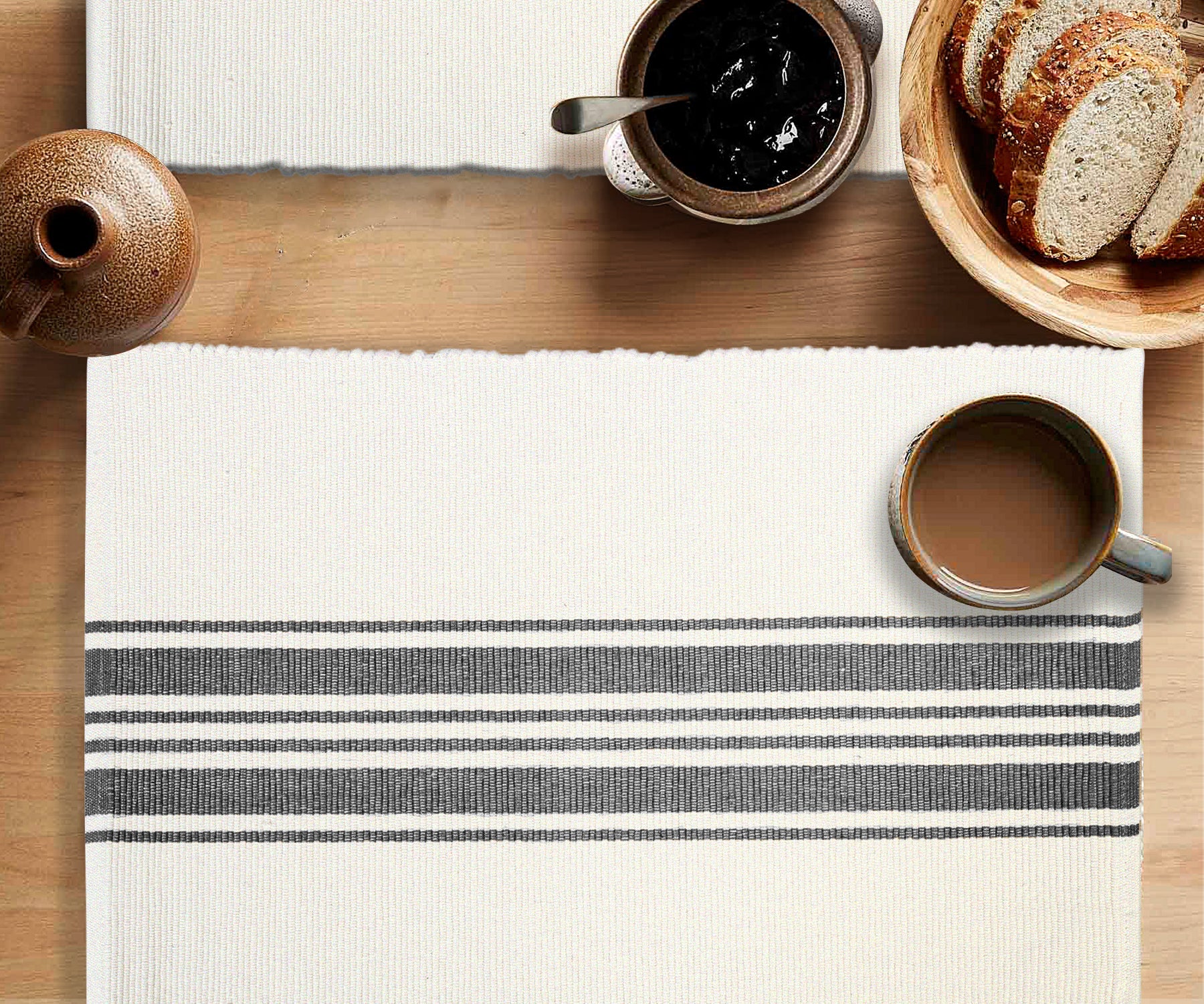 Overhead view of a white placemat with navy blue stripes on a wooden table, set with breakfast items.