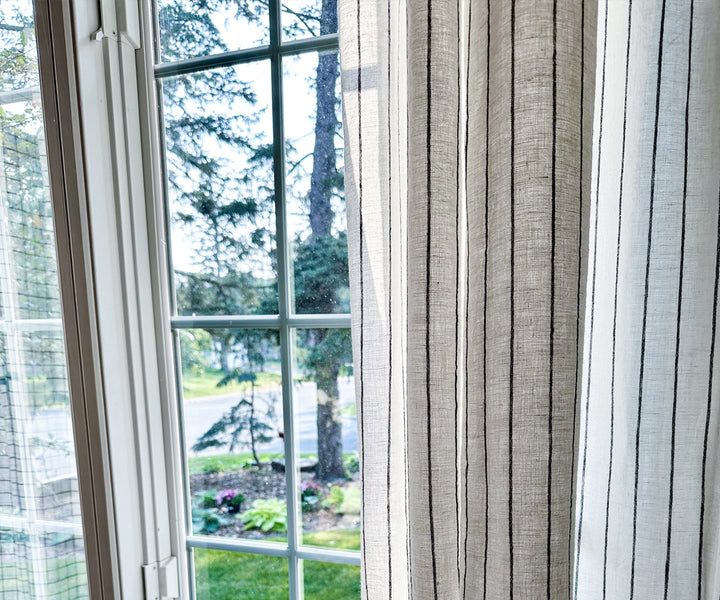 Striped curtains with white and blackline colors, hanging on a window and adding a touch of pattern to the room.