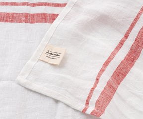 Close-up of a white linen towel with red french style stripes and a fabric tag