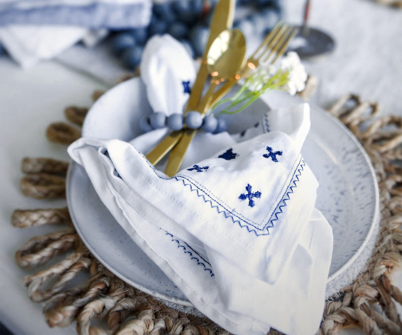 Elegant white napkins with intricate embroidered patterns on the edges.