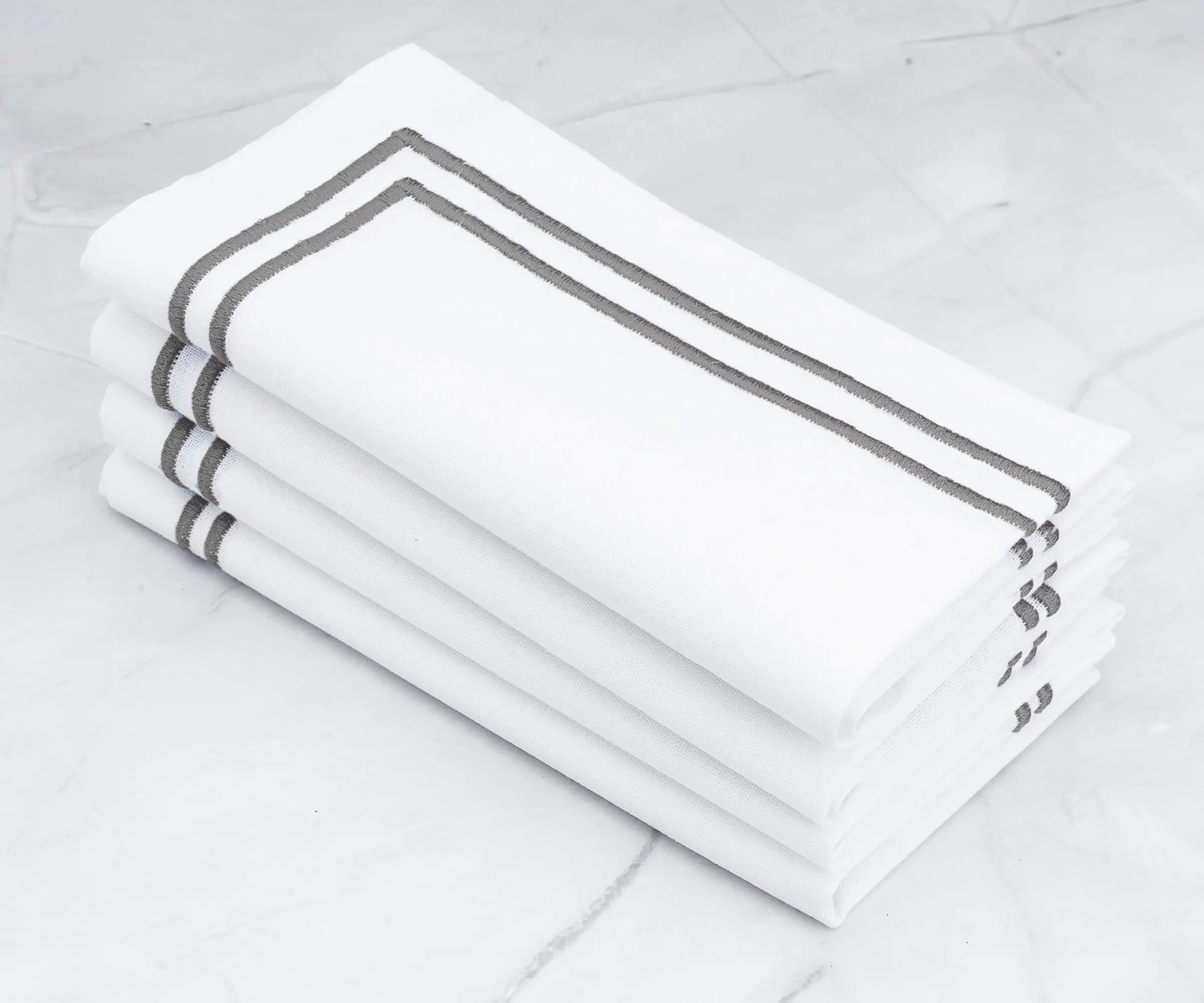 Neutral and versatile White napkins with gray embroidered lines.