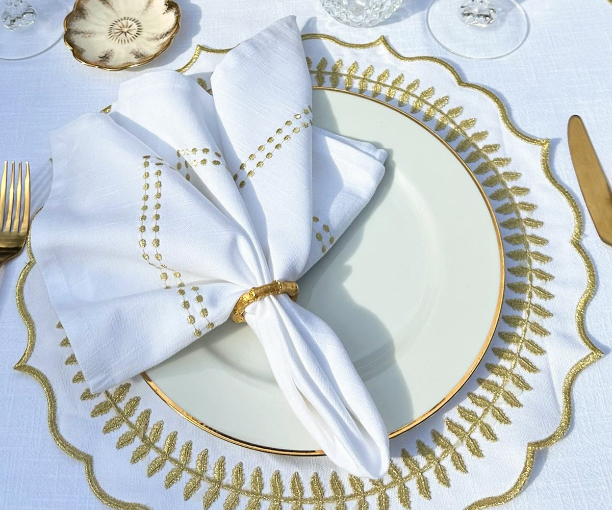 Set of round gold placemats with an elegant, woven texture, arranged neatly on a dining table setting.