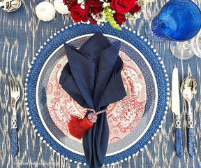 Blue and red themed table setting featuring a decorative napkin, ornate plates, and glassware.