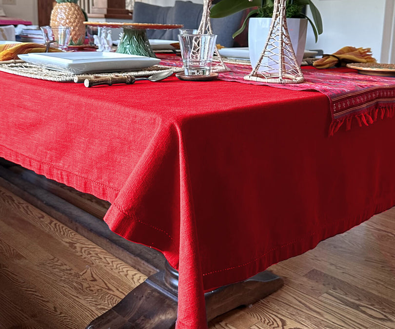 Elegant red hemstitched tablecloth with decorative stitching on a dining table.