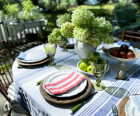 Soft red linen napkins in various earth tones, arranged in a casual, relaxed style on a vintage wooden table.