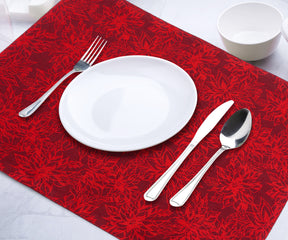 Red placemat with a floral pattern, set with white plate and silver cutlery.