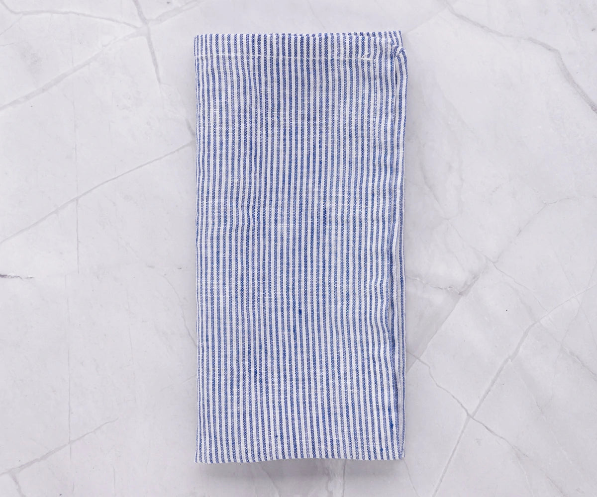 Set of 12 blue and white striped linen napkins arranged on a coastal-themed table