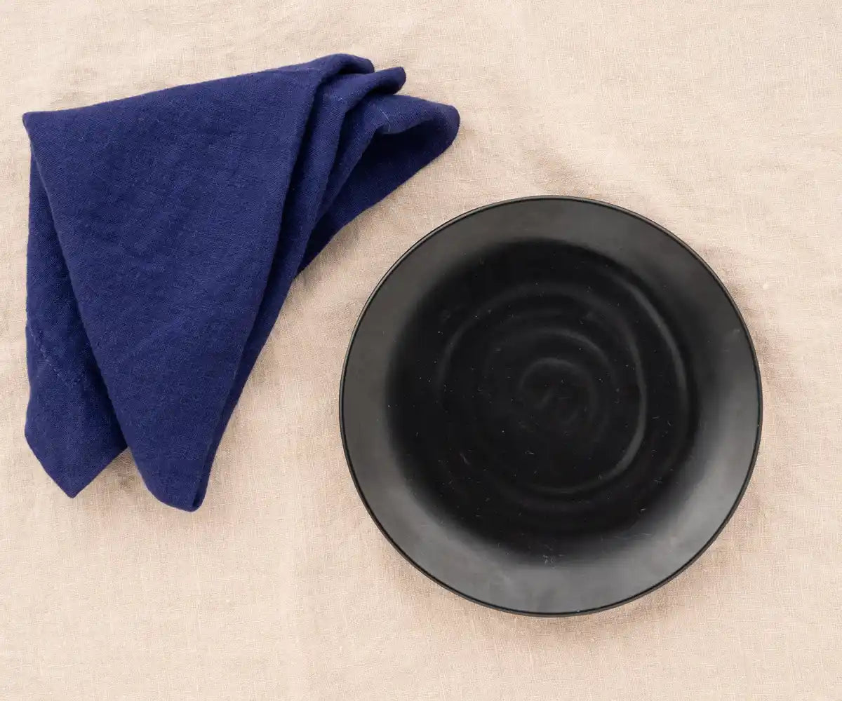 Blue linen plain dinner napkin elegantly folded on a dining table.