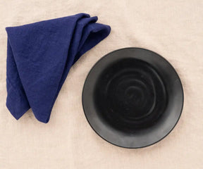 Blue linen plain dinner napkin elegantly folded on a dining table.