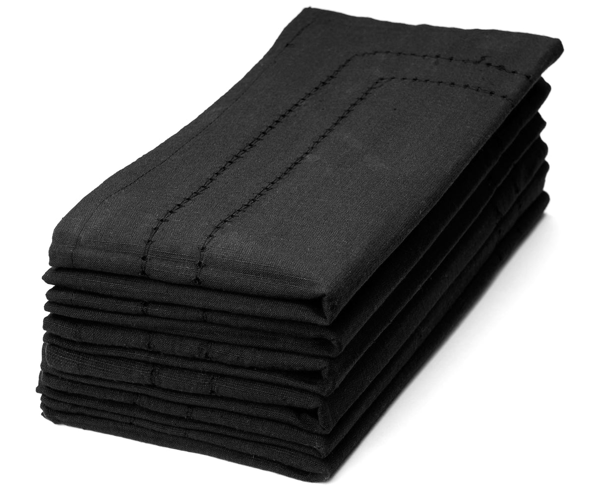 Elegant black napkins neatly folded and placed on a dining table, adding a touch of sophistication to the setting.