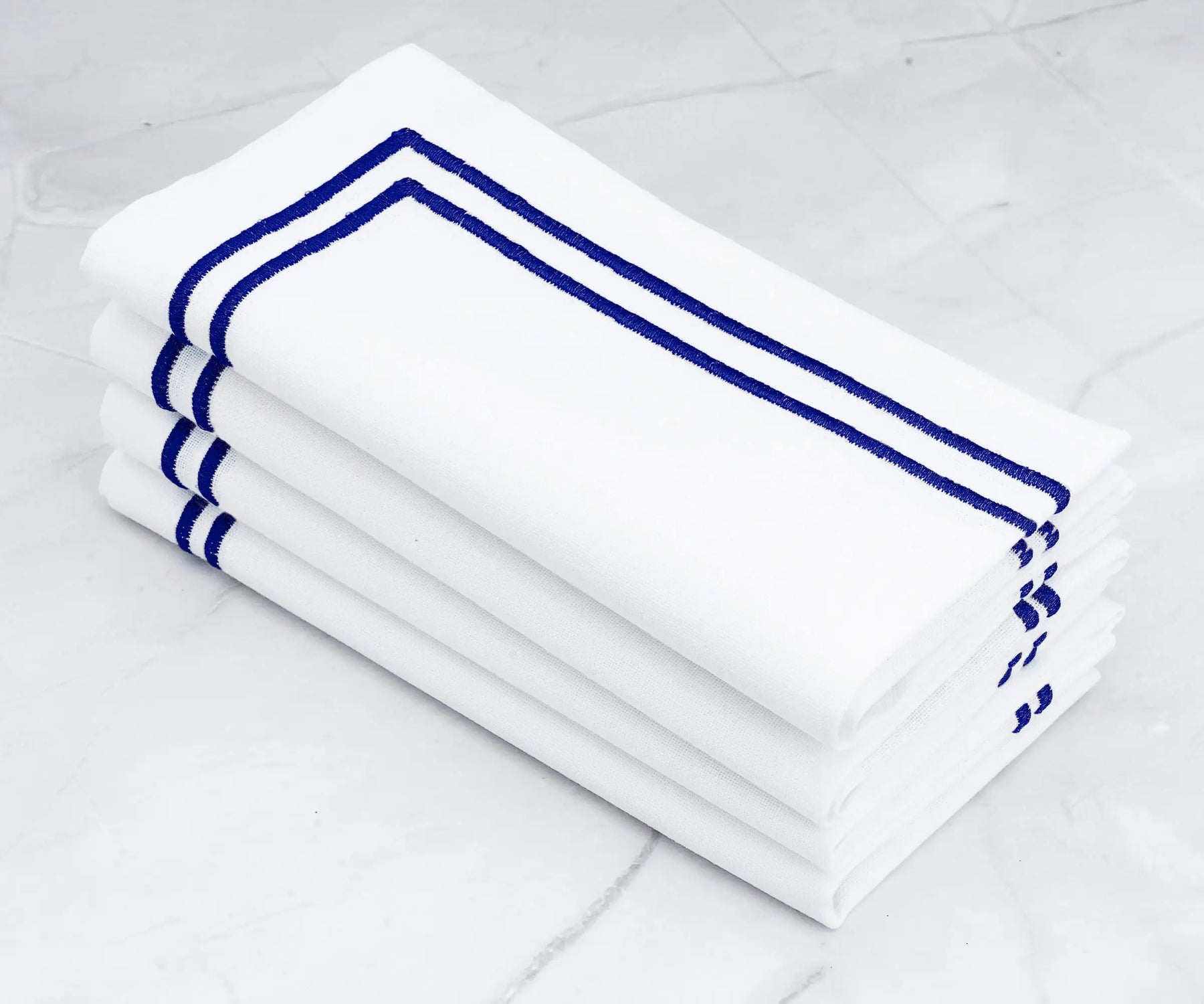 Fine linen napkins adorned with a double line of royal blue embroidery.