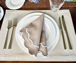 Beige scallop napkins elegantly draped over a vintage silverware set