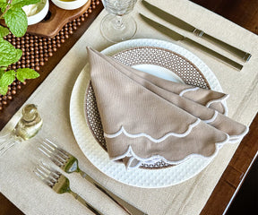 Close-up of finely stitched scallop edges on beige napkins.