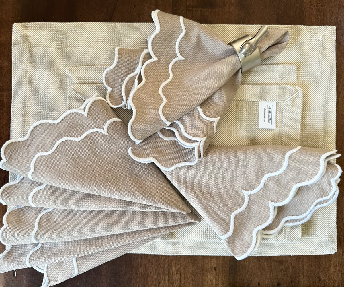 Beige scallop napkins arranged in a fan shape on a formal dining table