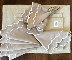 Beige scallop napkins arranged in a fan shape on a formal dining table
