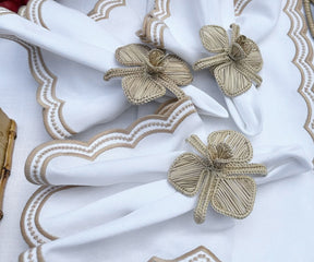 Set of beige scallop napkins displayed with matching tablecloth and centerpiece for a cohesive dining look.