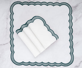 Beautifully crafted white napkins with dark green scalloped embroidery, folded elegantly on a table.