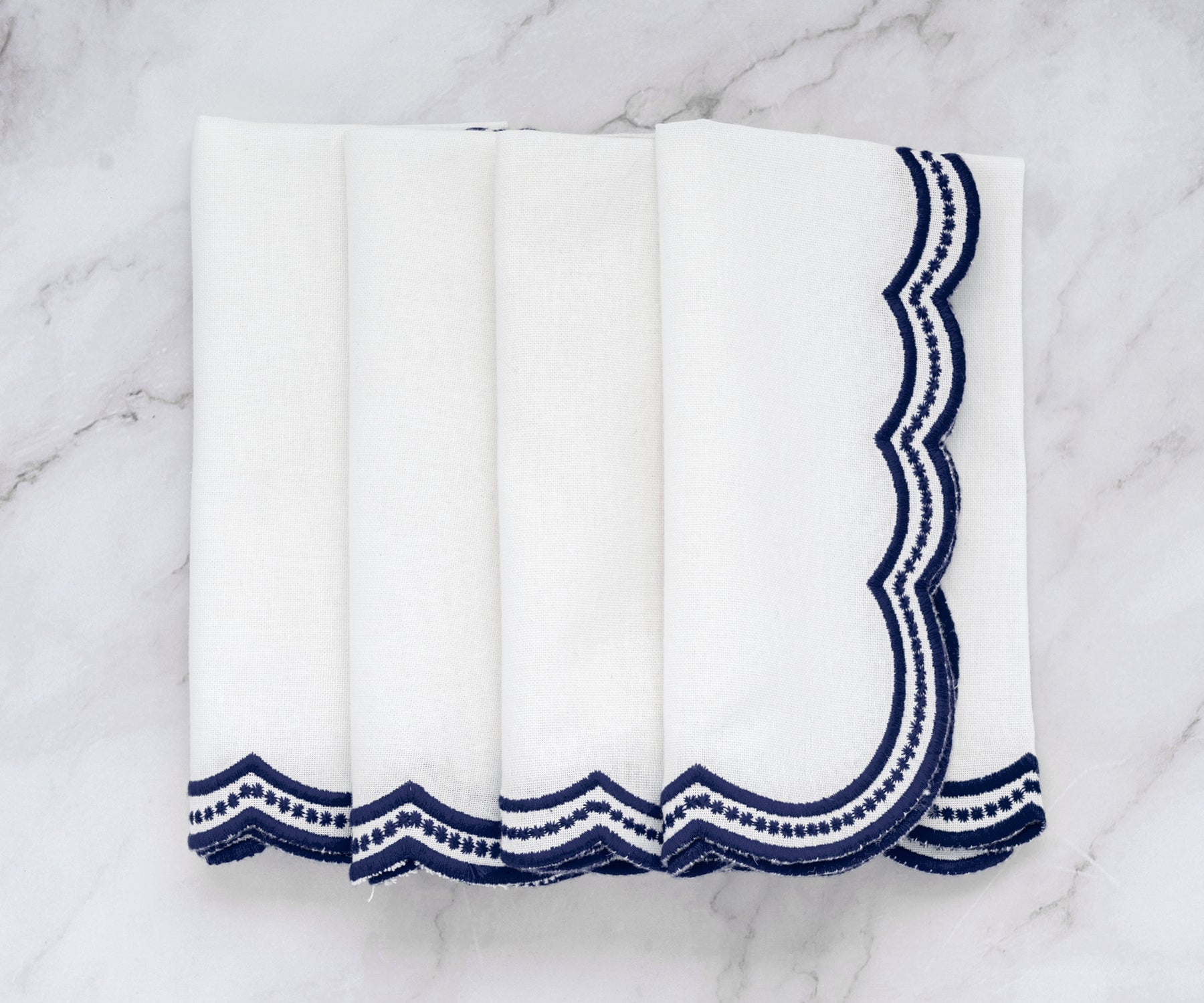 Stylish white napkins with delicate navy blue scalloped trim, adding a refined touch to any table.