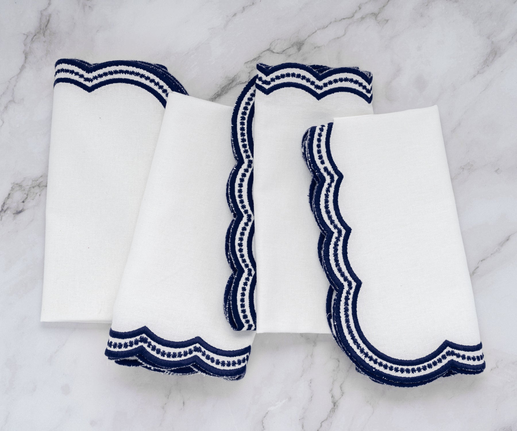 Luxury navy blue scalloped embroidered napkins on a marble surface, ideal for table decor.