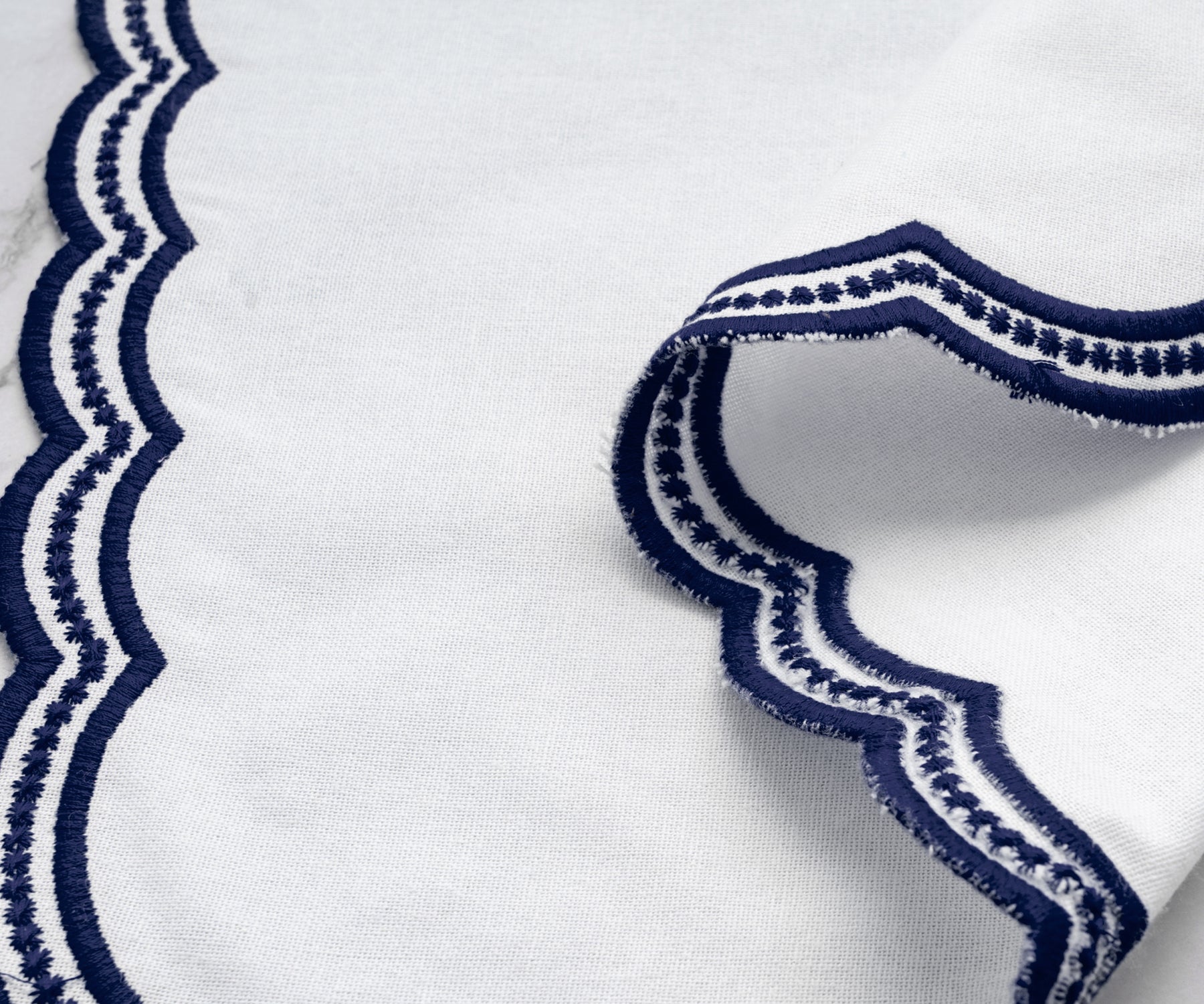 Luxury table napkin set with navy blue scalloped embroidery, crafted for elegant table settings.