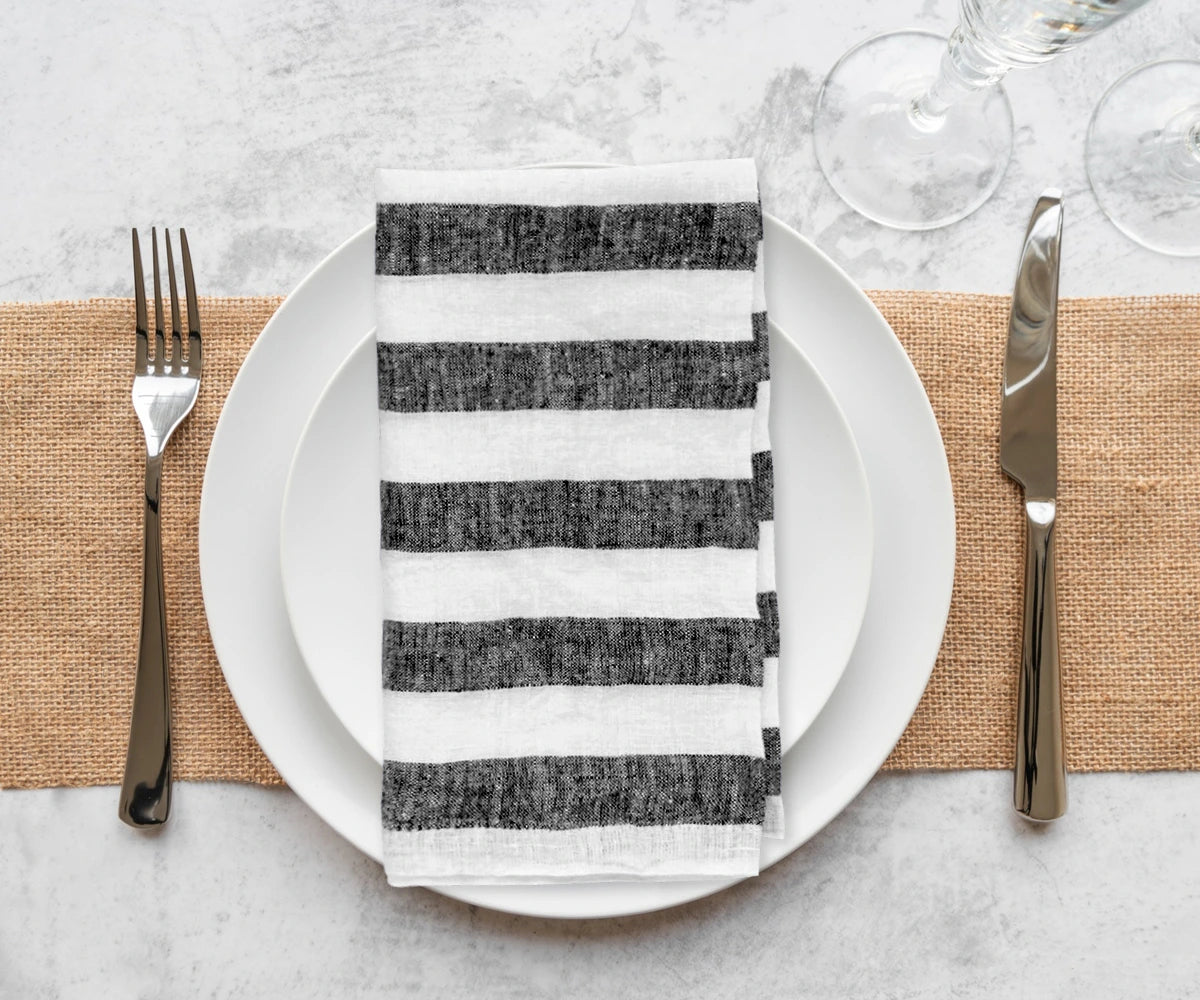 Delicately folded black napkins, displayed on a rustic table alongside handcrafted tableware, creating a warm, inviting atmosphere.