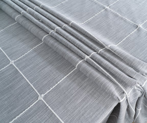 Durable and lightweight gray checked tablecloth with tassels, ideal for indoor and outdoor dining.