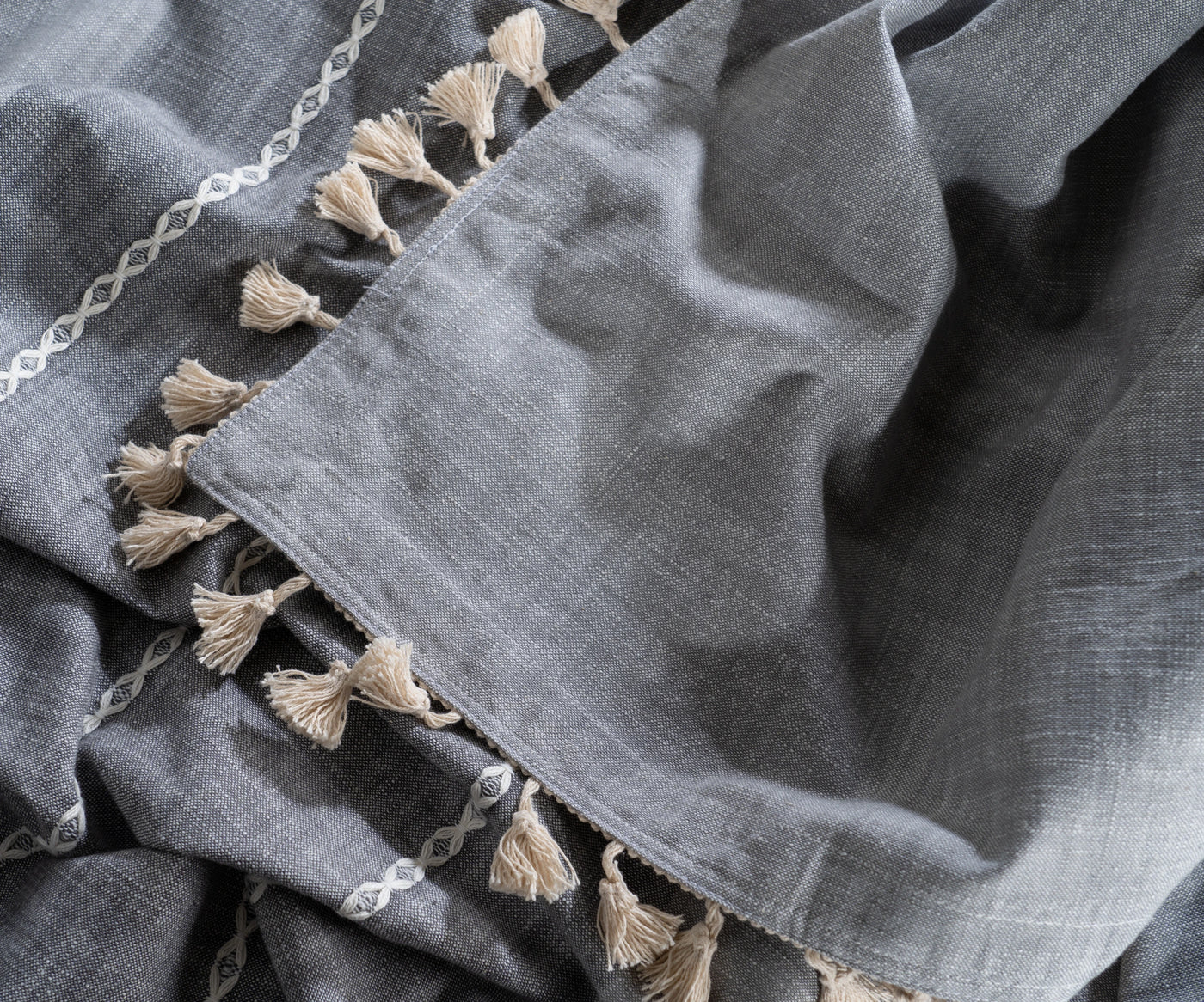 Gray tablecloth with bold stripes and tassel edges, great for contemporary table decor.