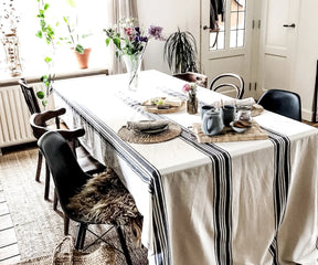 Dining room with a country striped navy tablecloth, wicker placemats, and floral decor.