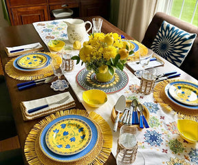 Table with gold-edged napkins, yellow plates, and floral centerpiece.