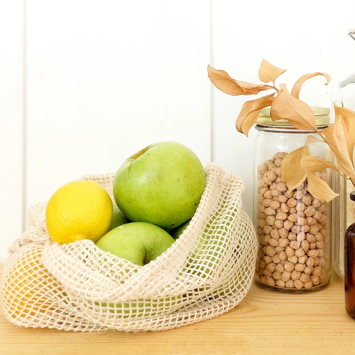 vegetable storage bags - Reusable produce bags hung on hooks in a zero-waste kitchen.