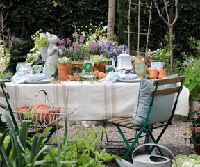 Garden table with striped tablecloth, terracotta pots, and wildflowers.