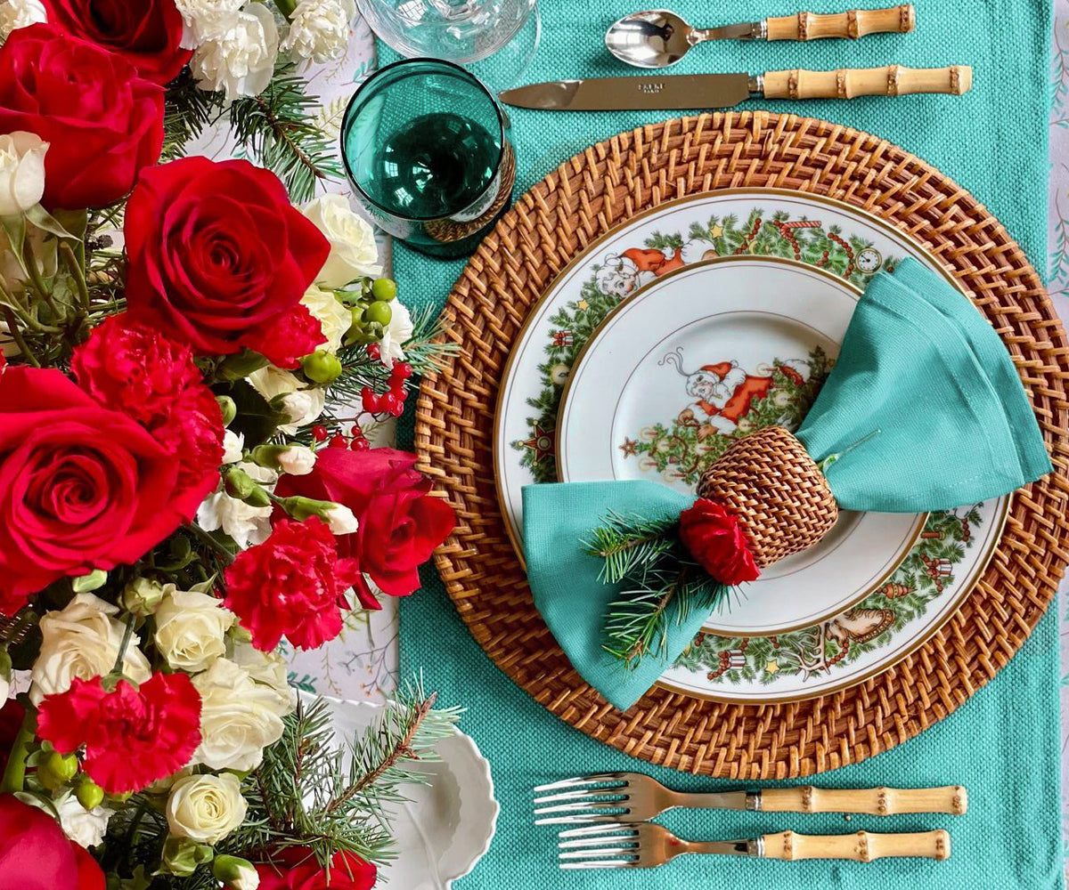 Light blue napkin with a wicker ring on holiday-themed plates and a festive centerpiece.